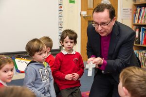 Bishop Philip Mounstephen shows his pectoral cross to a group of children from Ladock School